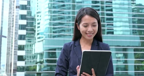 Professional Woman Using Tablet in front of Glass Building