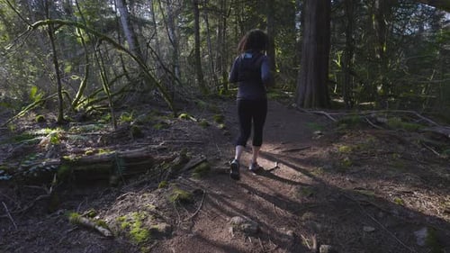 Caucasian Woman Trail Running in the Green Forest