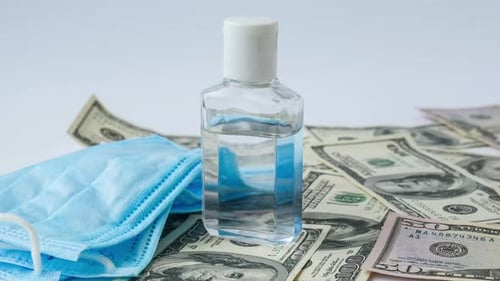 Vergrößern Sie den Stapel von Bargeld-Dollars und Antiseptikum für medizinische Masken