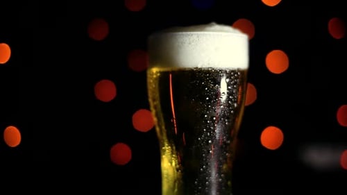 Ein Glas kaltes Bier auf schwarzem Hintergrund mit farbigen Lichtern