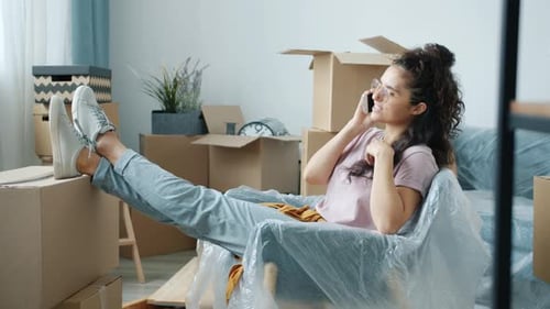 Young Woman Relaxing on Phone Among Moving Boxes