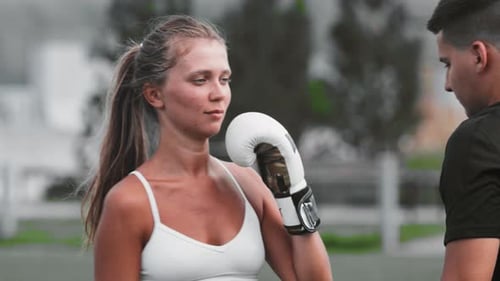 Young Woman Boxing With Trainer in City