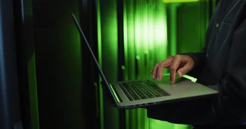 Mittelteil eines asiatischen männlichen IT-Technikers, der einen Laptop benutzt, um den Computerserver zu überprüfen