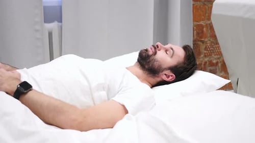 Man Waking Up and Checking Smartwatch in Bed