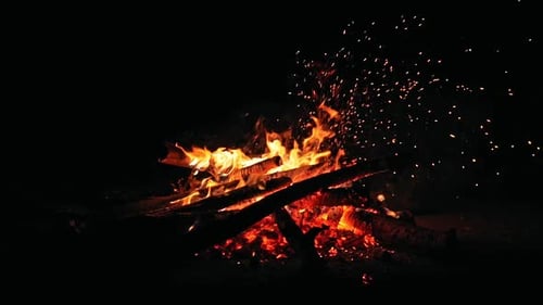 Campfire Burning Brightly at Night with Flying Embers