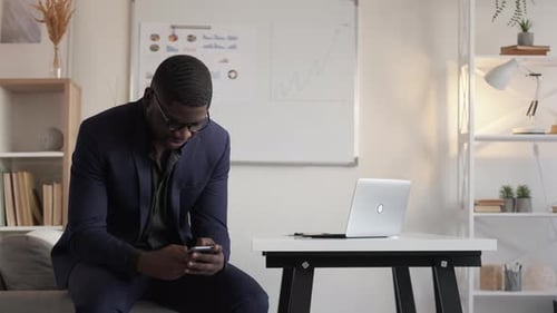 Man in Suit Using Smartphone at Home Office