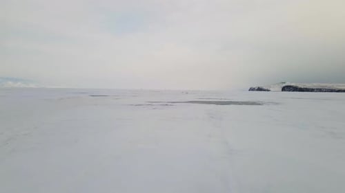 Baikal Lake Landscape with Cracked Frozen Ice Surface Covered with Snow in Winter