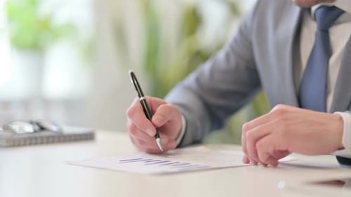 Close Up of Businessman Writing on Paper with Pen