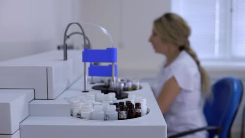 Operator of the Biochemical Analyzer Coronavirus, a Woman Is Not in Focus, Closeup Side View.