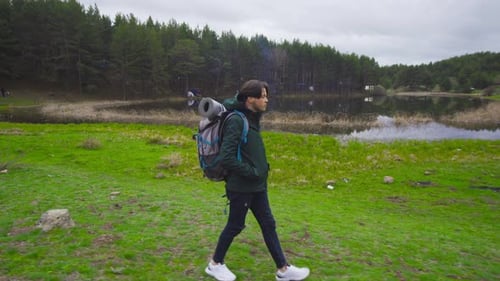 Young Adult Hiking Past Lake in Rural Setting