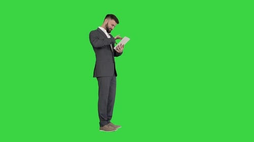 Businessman Standing and Using Tablet Computer on a Green Screen Chroma Key