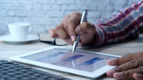 Man's Hand Working on Digital Tablet at Office Desk, Using Self Created Chart