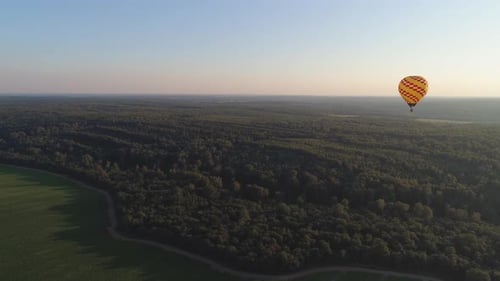 Hot Air Balloon Gliding over Vast Green Landscape