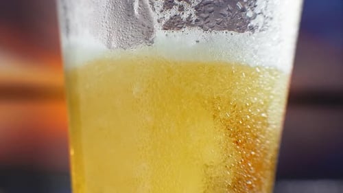 Slow-motion Macro Cold Beer Is Poured Into a Glass with Perspiration. Beer Bubbles Rise To the
