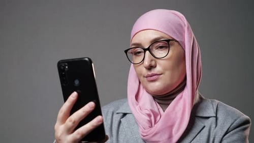 Muslimische Frau im Hijab surft lächelnd in den sozialen Netzwerken