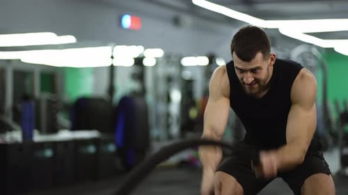 Focused Muscular Man Working Out in the Gym Using Battle Ropes