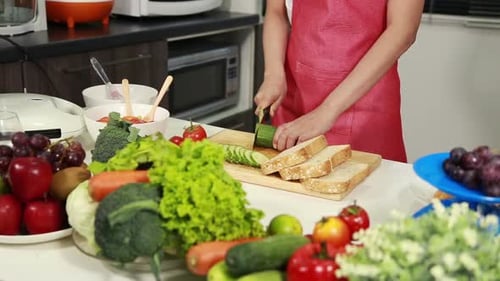 close up of hand cutting cucumber on board in kitchen room