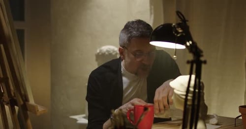 Artist Drinking and Eating in Studio
