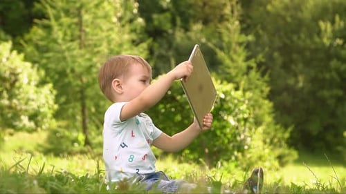 Boy Using Tablet Computer in Park