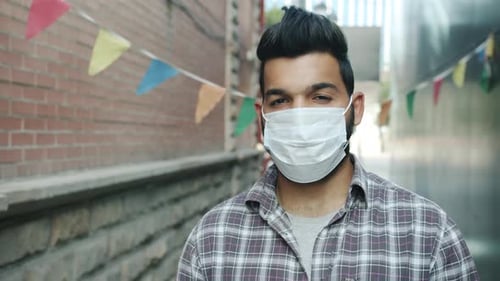 Portrait of Serious Arab Man Wearing Medical Face Mask Standing Outdoors in City