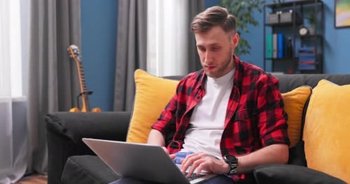 Young Adult Using Laptop on Couch Indoors