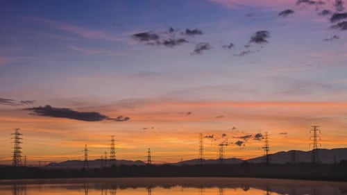 Dramatic Sunrise with Electrical Towers and Water Reflection