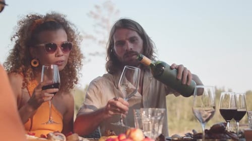 Friends Share Wine and Food at Outdoor Table