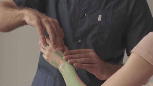 Applying Kinesiology Tape to Wrist in Medical Office