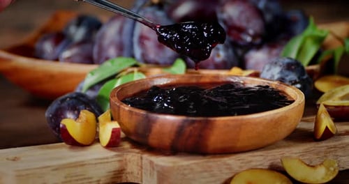 La main d'un homme avec une cuillère permet de retirer la confiture des prunes
