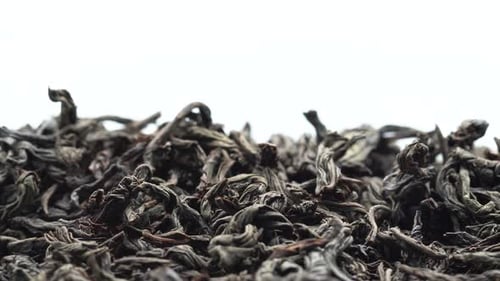 Trockene schwarze Teeblätter werden eingegossen, Tee kommt auf den Tisch