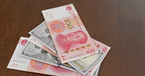 Chinese Yuan and US Dollars on Wooden Table
