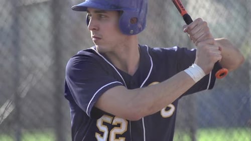 A young man practicing baseball at the batting cages.