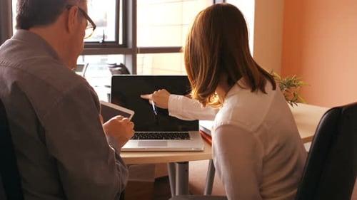 Team Collaboration at Table with Laptop and Tablet