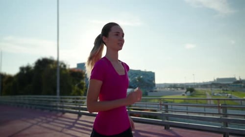 Young Woman Running on Urban Bridge on Sunny Day