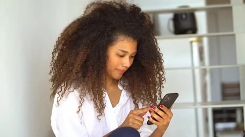 Woman Uses Smartphone, Smiles Indoors