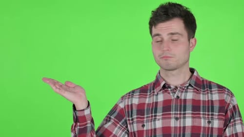 Portrait of Young Man Holding Product in Hand Green Chroma Screen