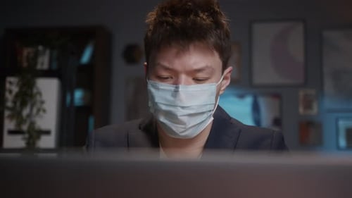 Young Adult Wearing Mask Working at Computer