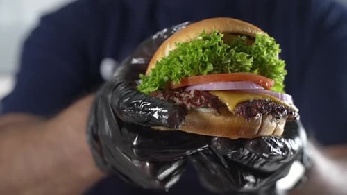 Gourmet Burger Held in Gloved Hands