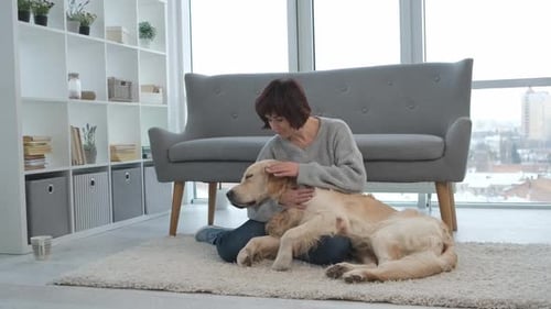 Woman Cuddling Golden Retriever Dog in Apartment