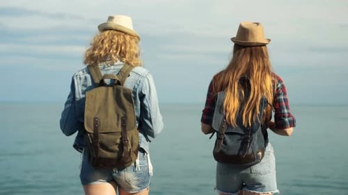 Young Girls Travelers with a Backpacks Going on a Beautiful Beach
