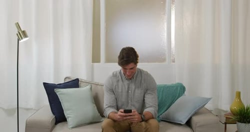 Man Interacting with Smartphone on Sofa