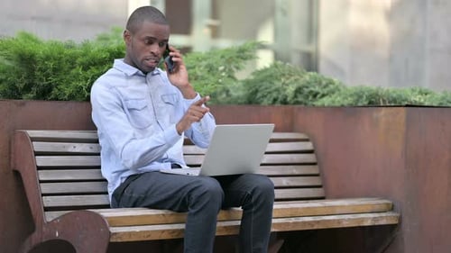 Young Adult Working and Talking on Phone in Park