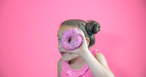 Attractive Cute Little Girl Holding Donuts with Icing To Her Hands Smiling Looks at the Camera and