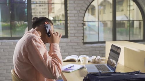Young Adult Working at Desk on Laptop and Phone