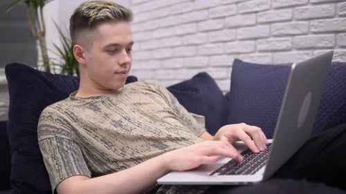 Young Adult Relaxing at Home Typing on Laptop