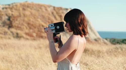 Woman Filming with Vintage Camera in Golden Field