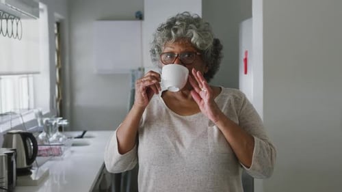 Senior Woman Drinking From White Mug at Home