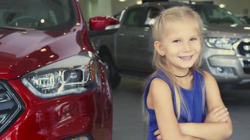 Smiling Child in Car Dealership by a Car