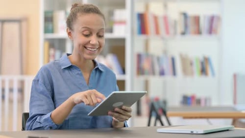 Serious Professional African Woman Using Tablet in Library
