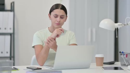 Woman Rubbing Wrist While Working at Office Desk